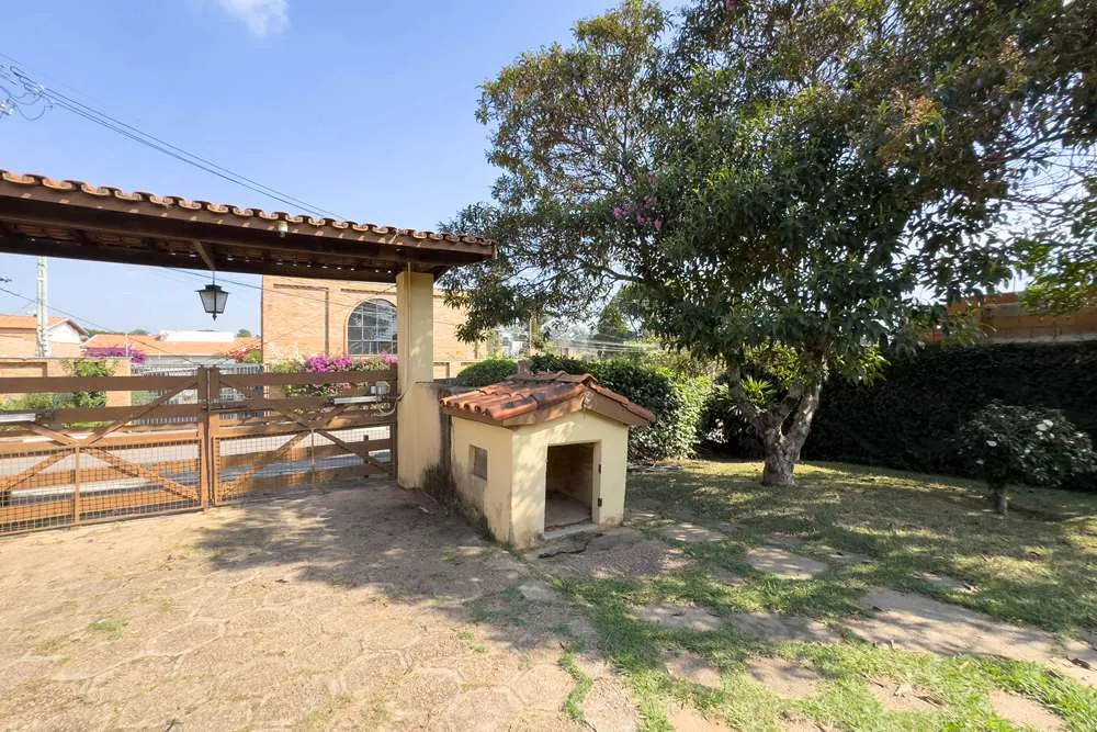 Portão de madeira e caminho de pedra · Casa térrea em terreno arborizado em Vinhedo