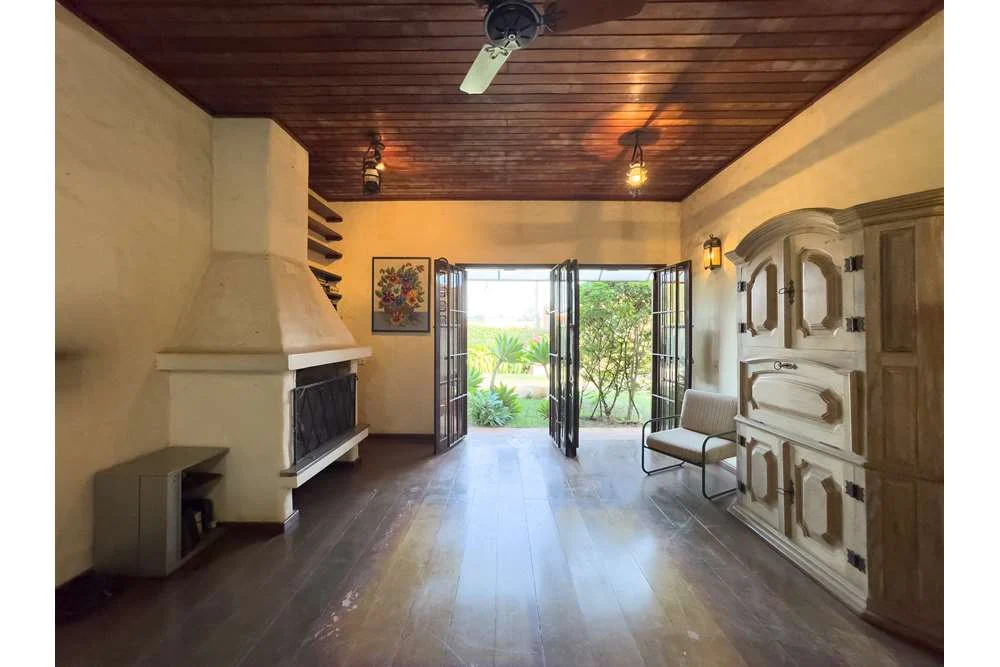 Sala com portas abertas para o jardim · Casa térrea em terreno arborizado em Vinhedo