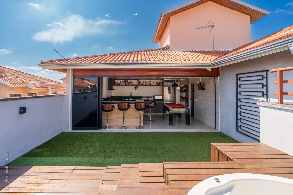 Deck de madeira, gramado e a jacuzzi no canto do terraço · Cobertura com terraço, jacuzzi e espaço gourmet em Vinhedo