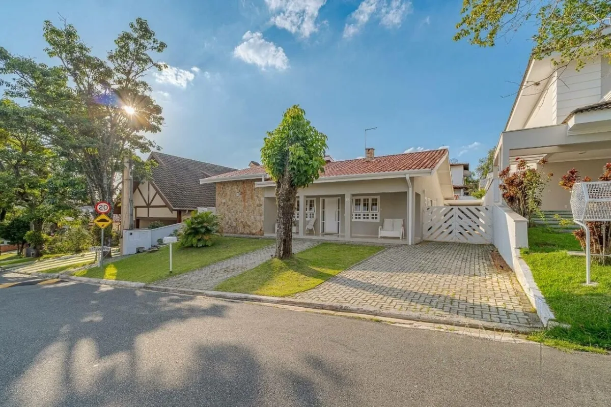 Fachada em pedra, recuada da rua, com jardim na frente · Casa térrea com lareira e espaço gourmet em Vinhedo