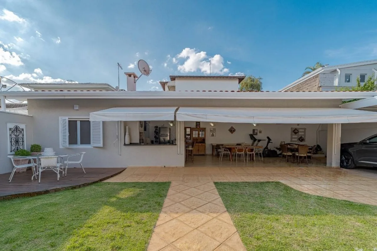 Gramado, piso e a cobertura contínua ao fundo · Casa térrea com lareira e espaço gourmet em Vinhedo