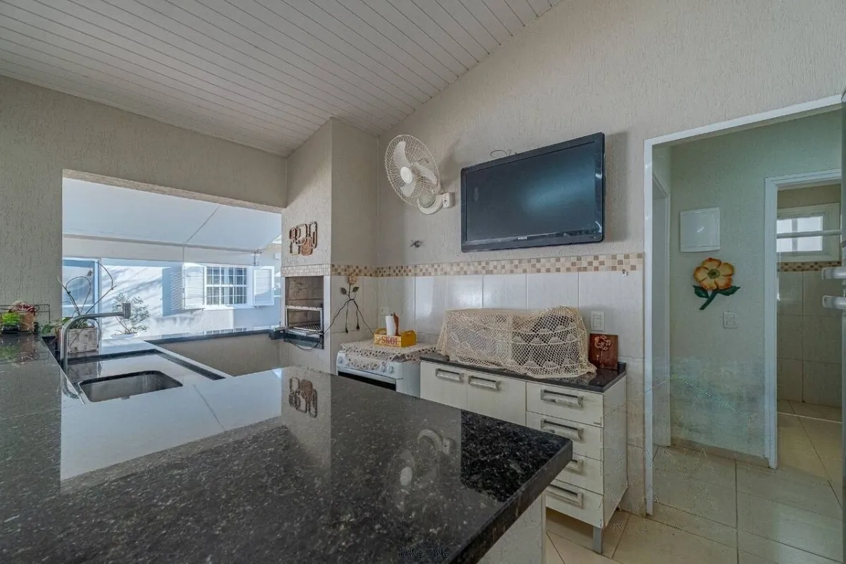 Cozinha de apoio do gourmet, em granito preto · Casa térrea com lareira e espaço gourmet em Vinhedo