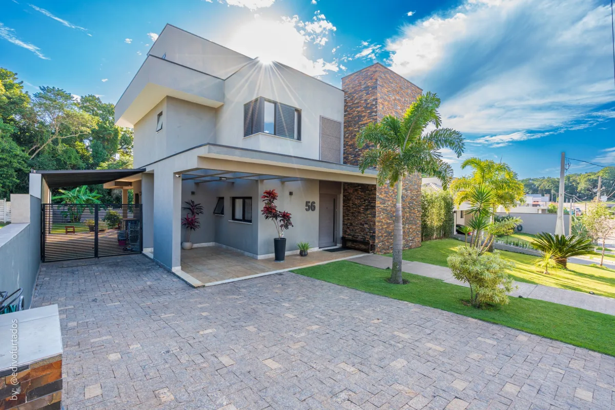 Fachada contemporânea, com o volume em pedra e a garagem coberta · Casa com piscina, gourmet e quintal plano em Itupeva