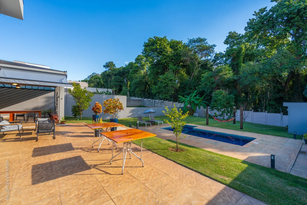 Piscina, deck em pedra e o gramado que segue até a mata · Casa com piscina, gourmet e quintal plano em Itupeva